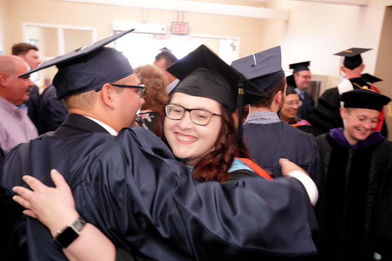 Two graduates hugging each other immediately after the commencement ceremony