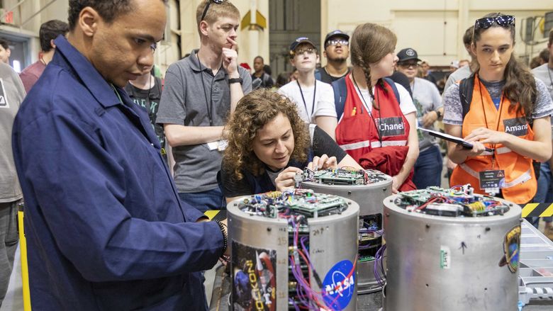 Students and NASA staff examining payloads before installing them in the rocket