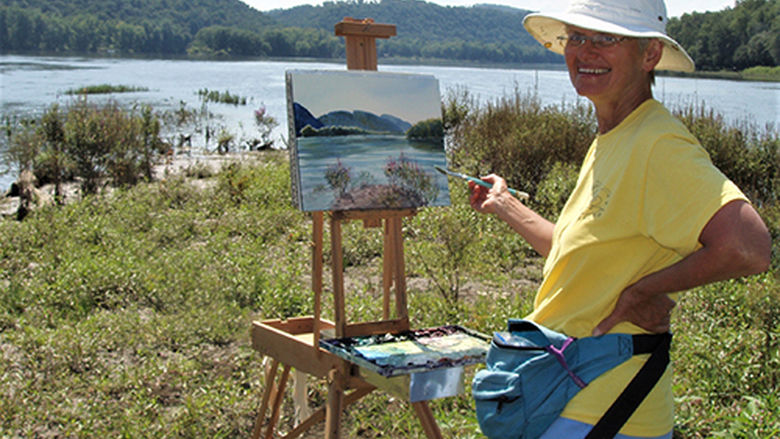 artist Sue Hand painting on a river bank