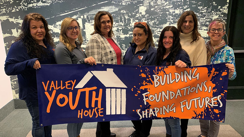 A group standing with a banner at Valley Youth House