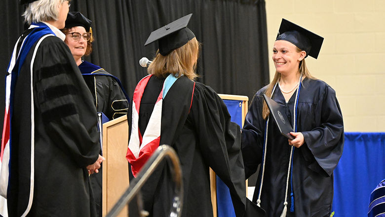 A woman at right receives her diploma.