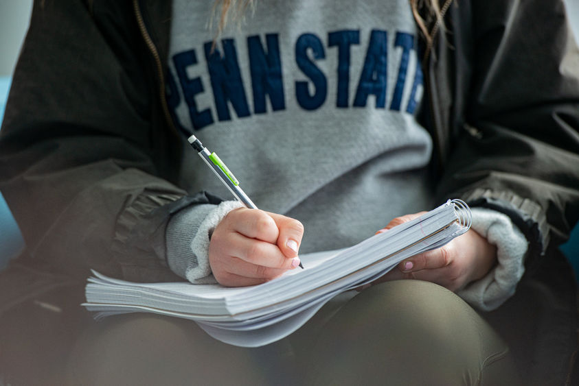 A close-up image of a student writing in a notebook.