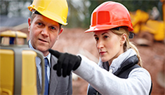 two surveyors, a man and a woman, examining a piece of surveying equipment and discussing two surveyors, a man and a woman, examining a piece of surveying equipment and discussing