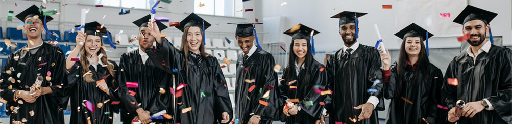 robed graduates standing in a row and waving their diplomas