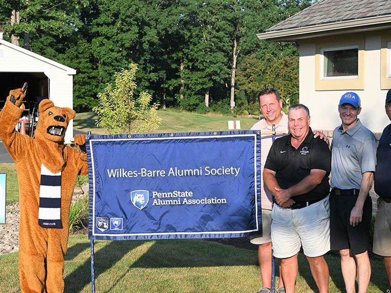 Golf tournament winners posing with the Nittany Lion