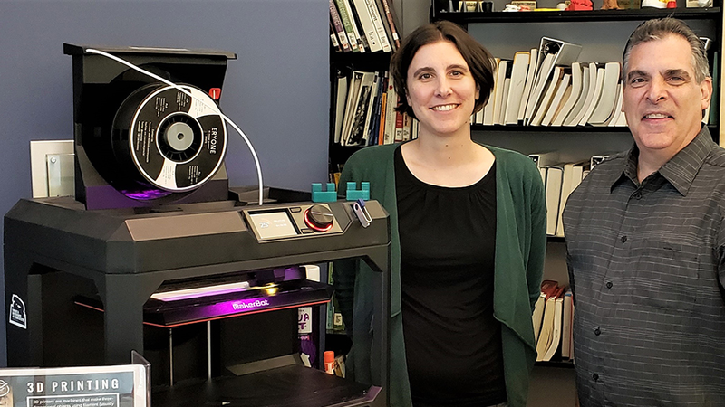 Jonathan Pineno (Friedman Art Gallery director) and Megan Mac Gregor (librarian) standing in front of the Nesbitt Library's 3D printer; two of the small green widgets are sitting on top. Jonathan Pineno (Friedman Art Gallery director) and Megan Mac Gregor (librarian) standing in front of the Nesbitt Library's 3D printer; two of the small green widgets are sitting on top.