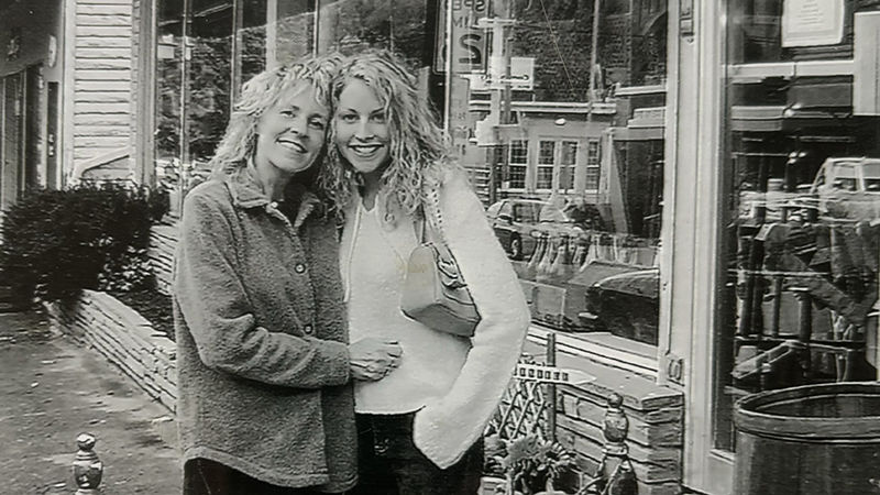 Two woman with their arms around each other standing outside a store