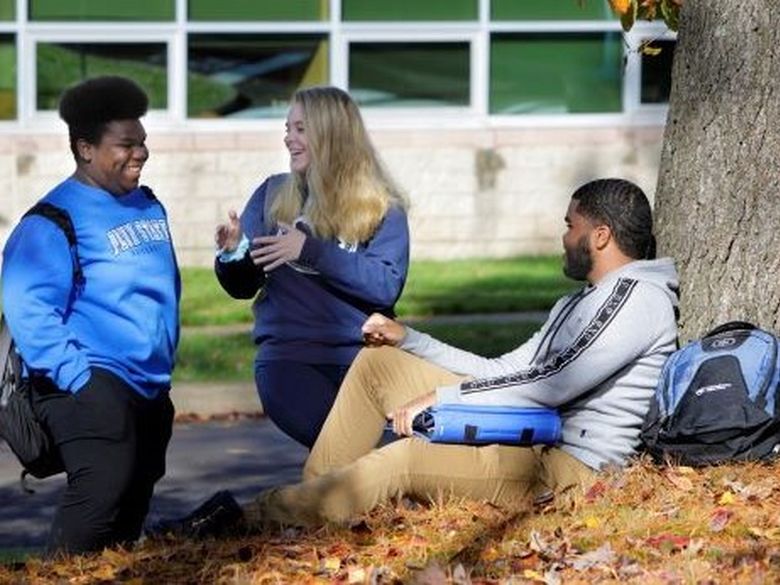 Three students outside talking to one another
