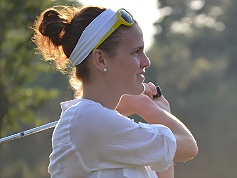 Woman in a white t-shirt and headband holding a golf club over her shoulder