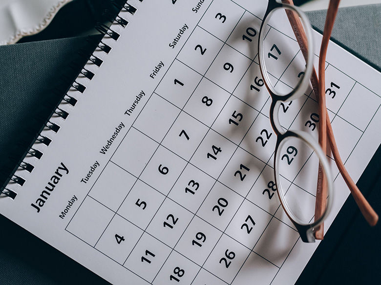 a calendar lying on a table with a pair of glasses resting on top of it