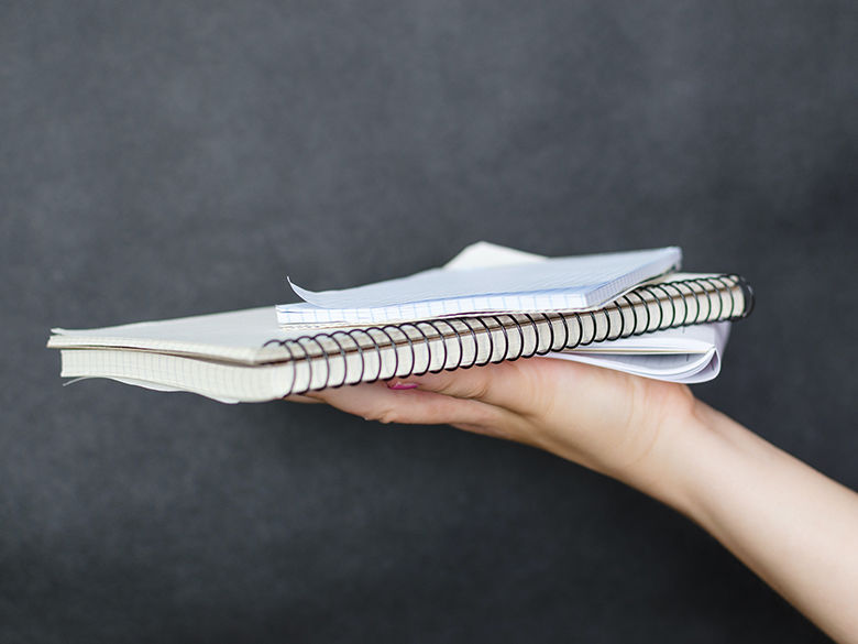 a hand holding out a pile of paperwork