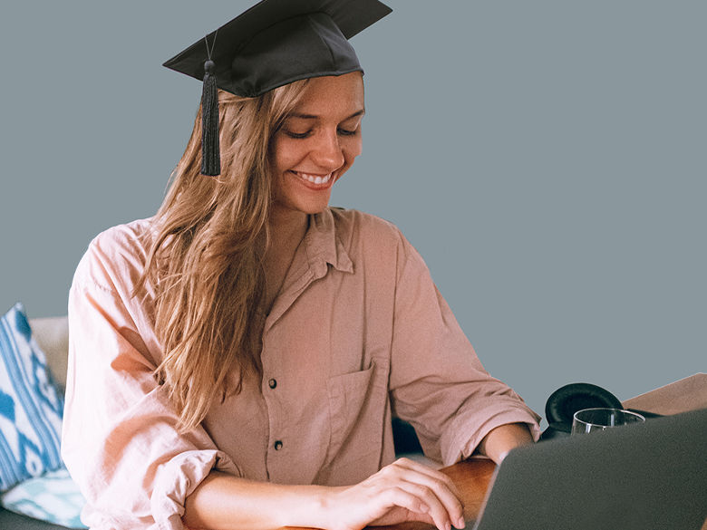 girl wearing mortarboard working on a computer