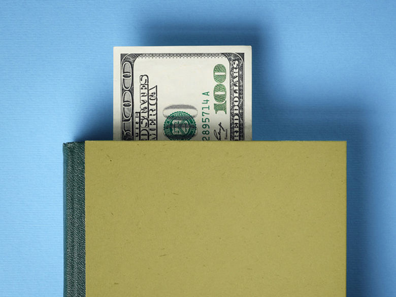 a $100 bill sticking out of the top of a book