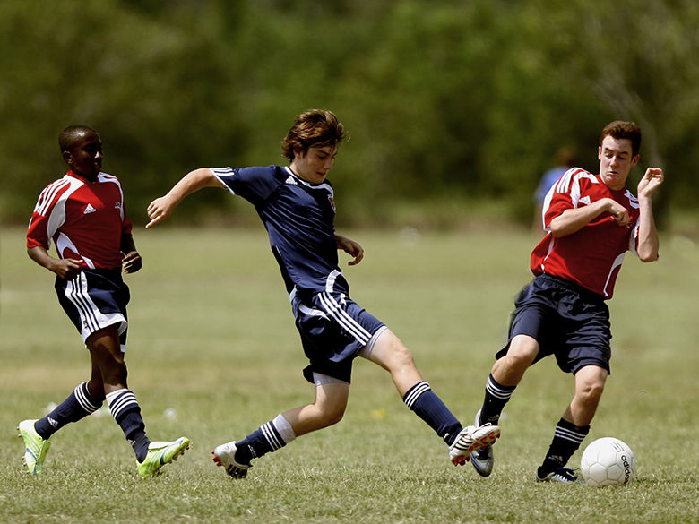 3 young men playing soccer