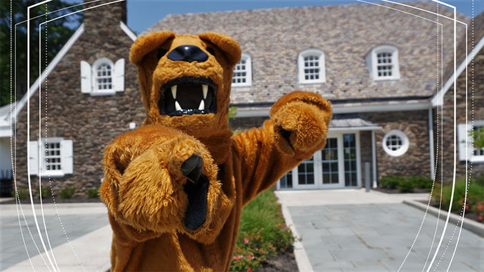 Nittany Lion mascot standing in front of student commons pointing directly at camera