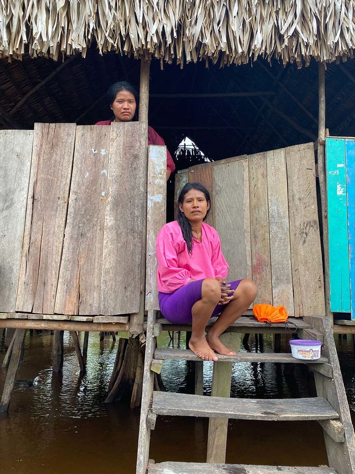 Two women in a thatched hut on a river