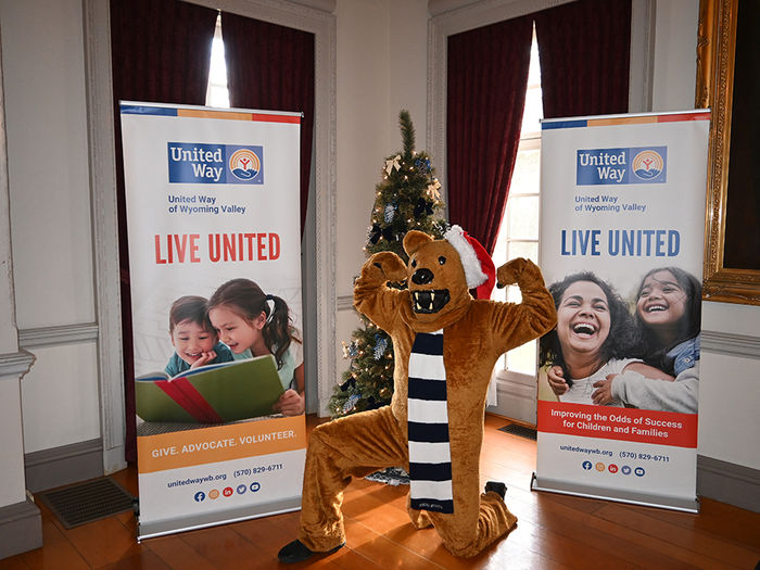 The Nittany Lion posing between two United Way posters.