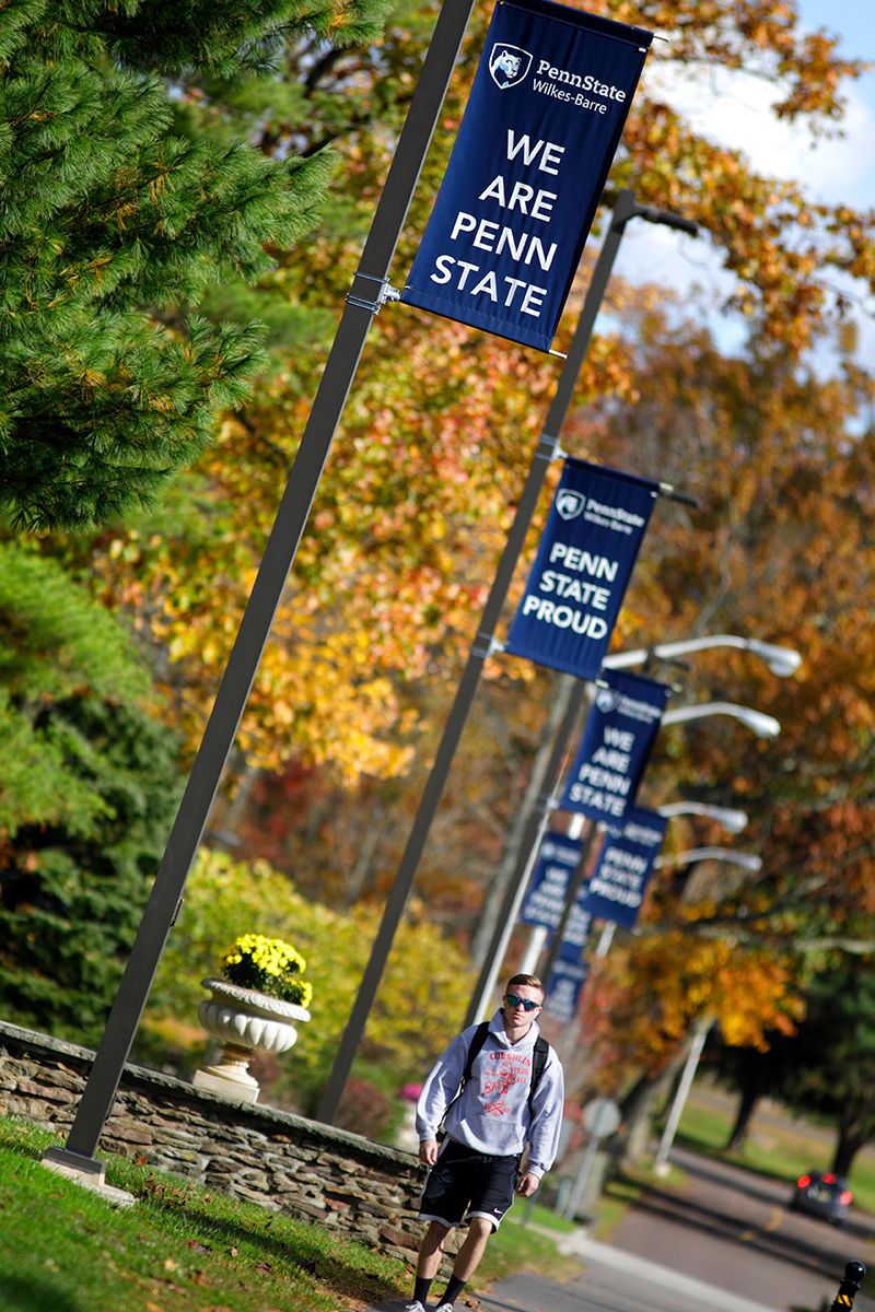 student walking across campus in fall foliage