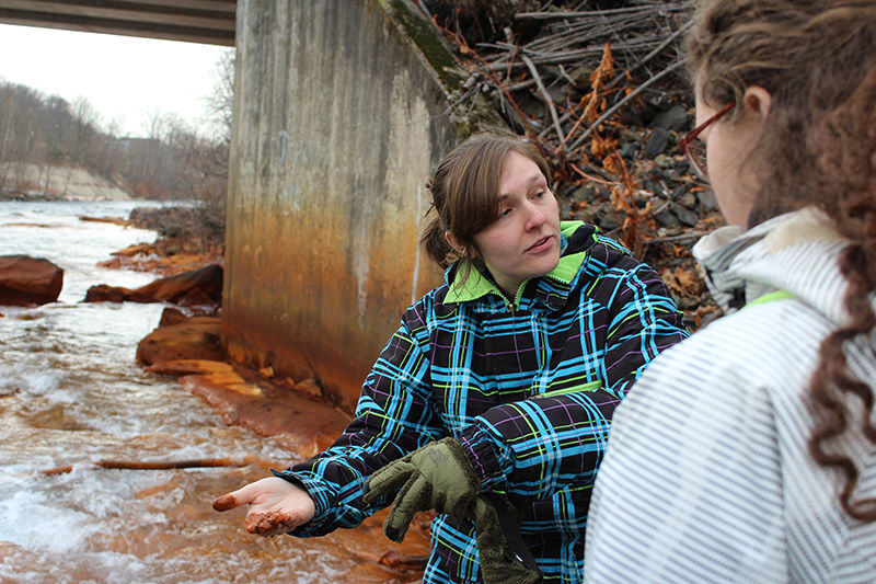 Instructor pointing out brown sediment in a stream