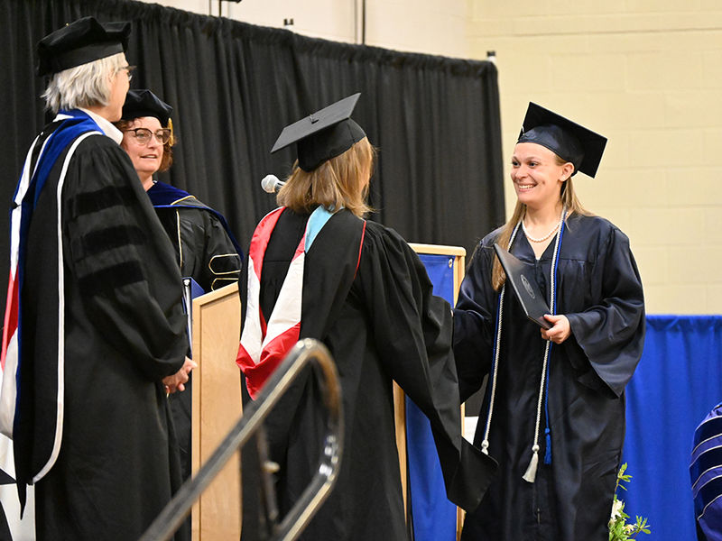 A woman at right receives her diploma.