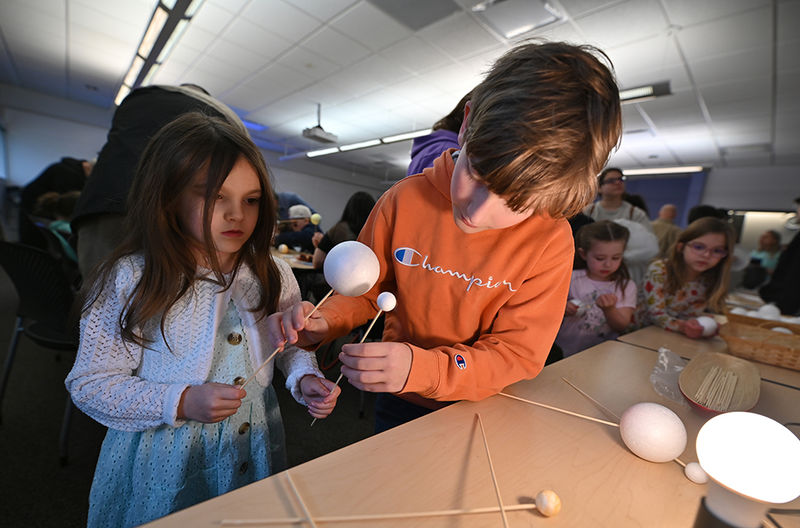 A young girl and boy working on an eclipse craft.