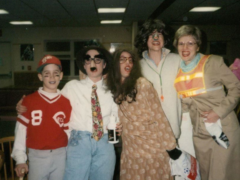 Five people standing in a row dressed in Halloween costumes.