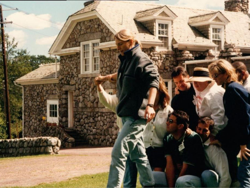 A group of people outside with a stone building behind them.