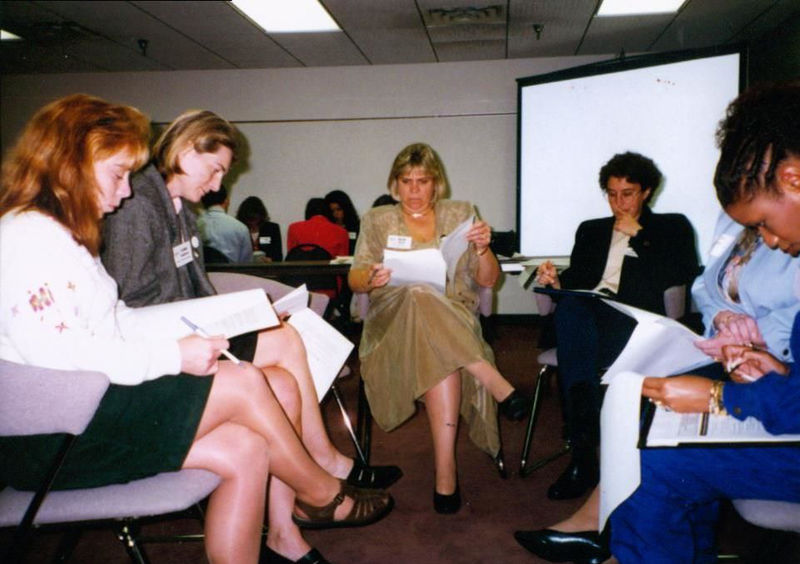A small group of people in a half circle working on a project.