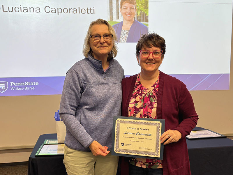 A woman at left presenting an award to a woman at right.