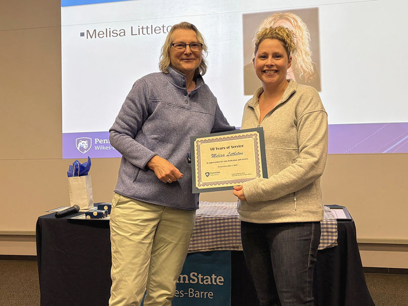 A woman at left presenting an award to a woman at right.