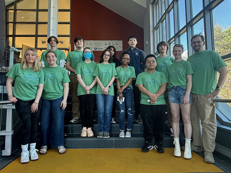 A group of students in matching green shirts promoting sustainability pose for a photo.