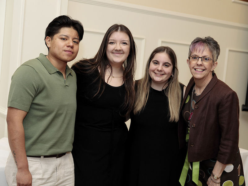 Four people standing alongside each other indoors.