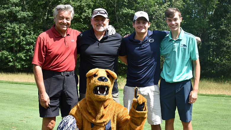 The winning team posing on the green with the Nittany Lion Mascot