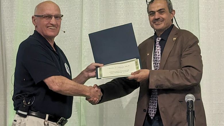 A man at right presenting an award to a man at left.