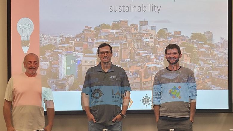 Three people standing against a presentation screen.