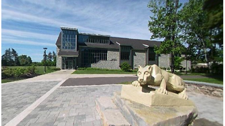 the Nittany Lion statue in the foreground; the Academic Commons building in the distance