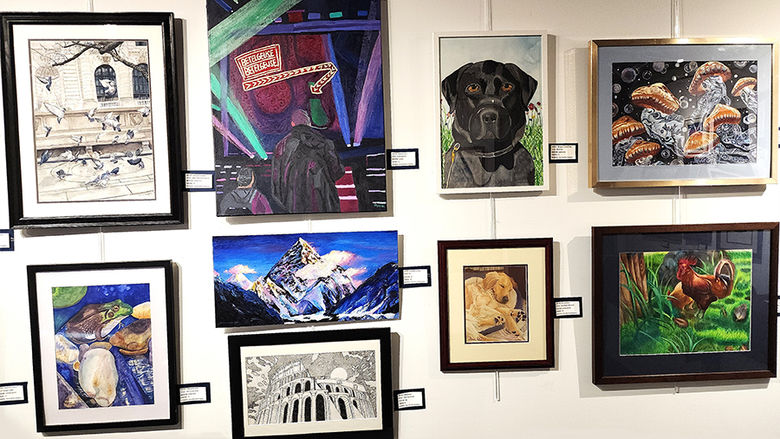 Nine pieces of artwork from the 5th Annual High School Art Exhibit hanging on the Friedman Art Gallery wall