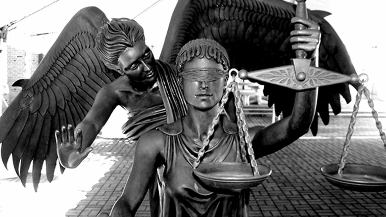 Bronze statue entitled “Justice tempered by Mercy.” Justice is blindfolded and holding scales. Mercy is winged and leaning over Justice’s shoulder from behind, holding her hand up with palm outward, as if to stay Justice’s sword. (Credit: Wikipedia)