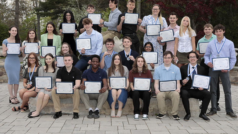 A large group of students posing outside around the Nittany Lion statue.