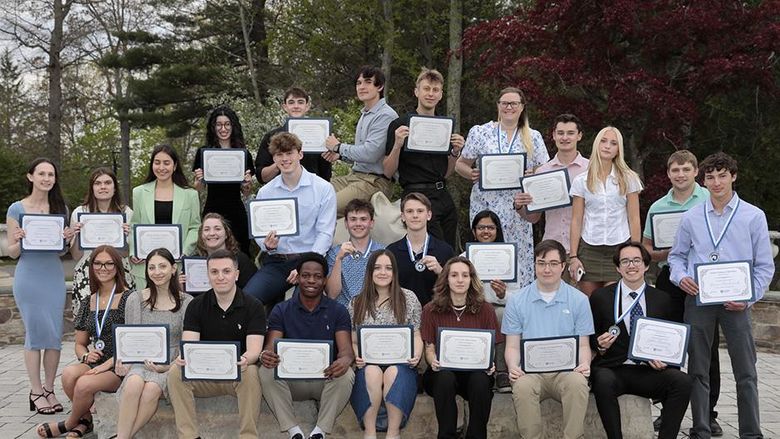 A large group of students posing outside around the Nittany Lion statue.