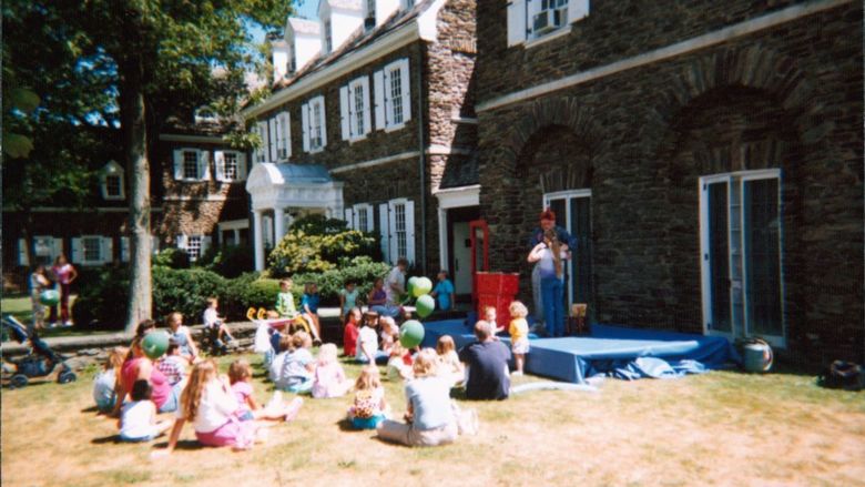 Children watching someone make balloon art outdoors.