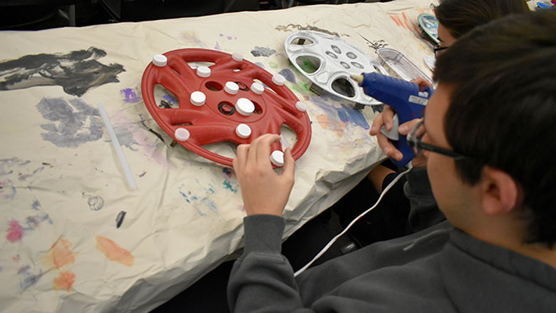 Student creating hubcap art