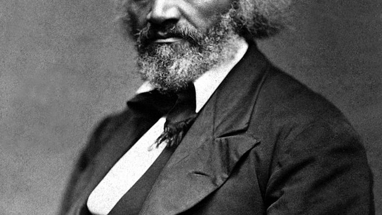 A man of color with a full head of hair and beard sits looking pensive in a portrait.