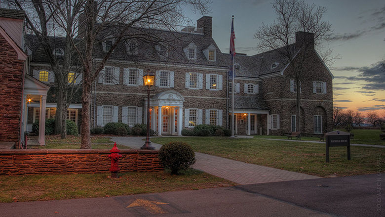 The front of Hayfield House at dusk, with warm lights in the windows