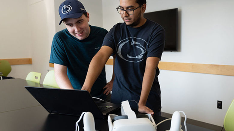 Two students standing and looking at a computer screen in a lab