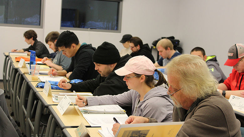 Students seated in a classroom, individually taking notes