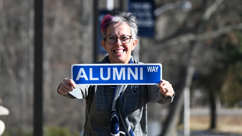 Jackie Warnick-Piatt holding Alumni Way sign