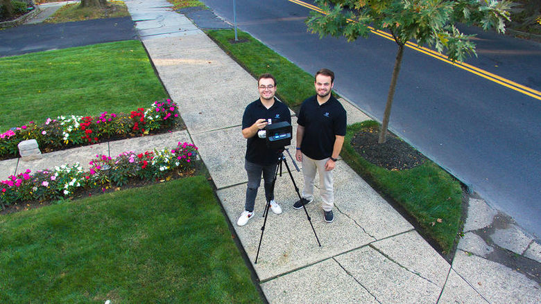 Matthew and Patrick Nelson standing with a 360-degree camera and tripod