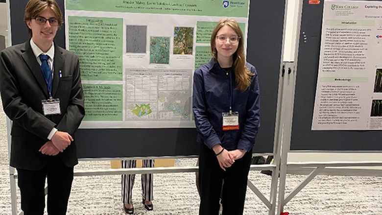 A male student at left and a female student at right stand in front of a poster titled “The Presence of Beech Leaf Disease in Two Pennsylvania State Parks.”
