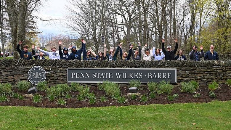 People standing behind the Penn State Wilkes-Barre sign